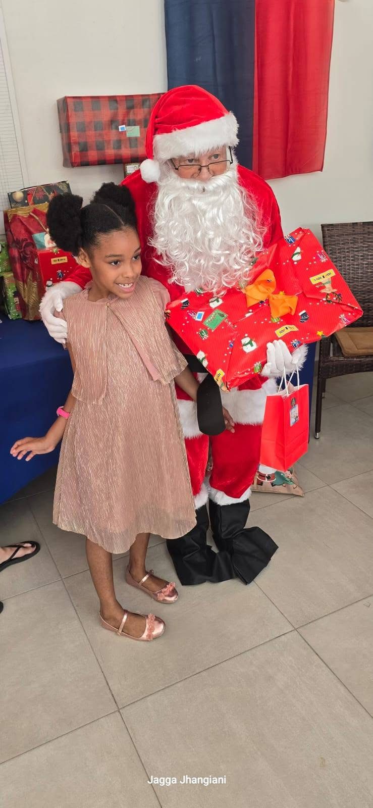 A smiling child standing beside Santa Claus and brightly wrapped presents
